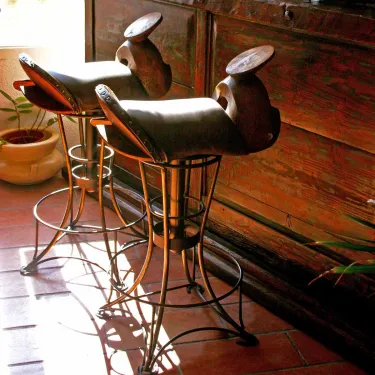 Chaise haute de bar pivotante - L'assise est en cuir et bois, le pied en fer forgé