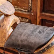 Chaise de bar pivotante avec une assise en bois et cuir. Le pied est en fer forgé